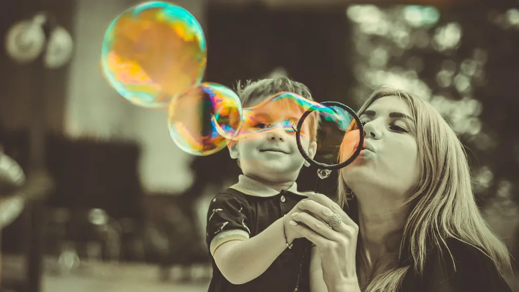 A mother and child enjoy blowing colorful bubbles together as a playful sensory activity