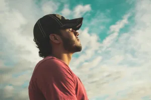 Man with closed eyes breathing in with blue skies