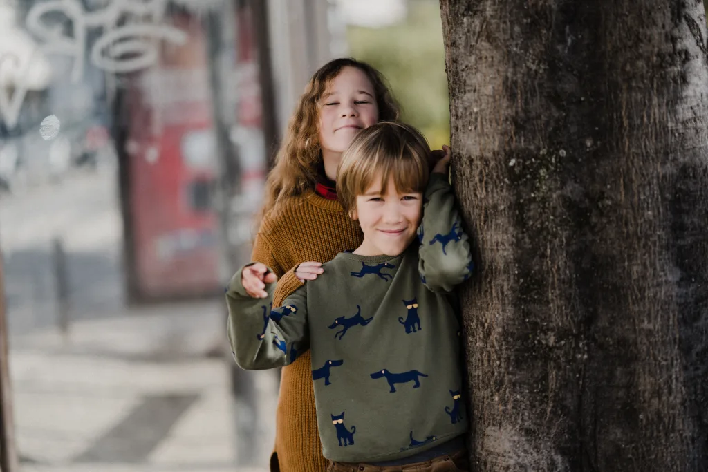 Young girl and boy next to a tree on the street