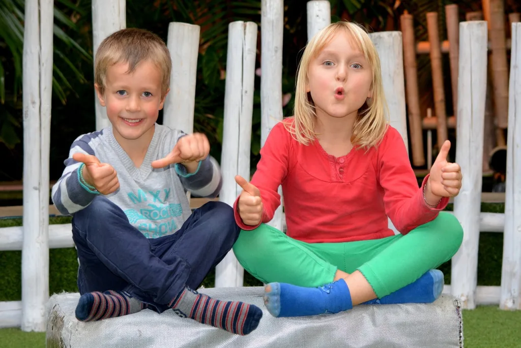 Young boy and girl with their thumbs up smiling at the camera