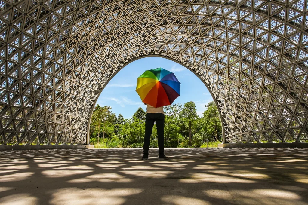 Person stood in a light tunnel with a rainbow umbrella