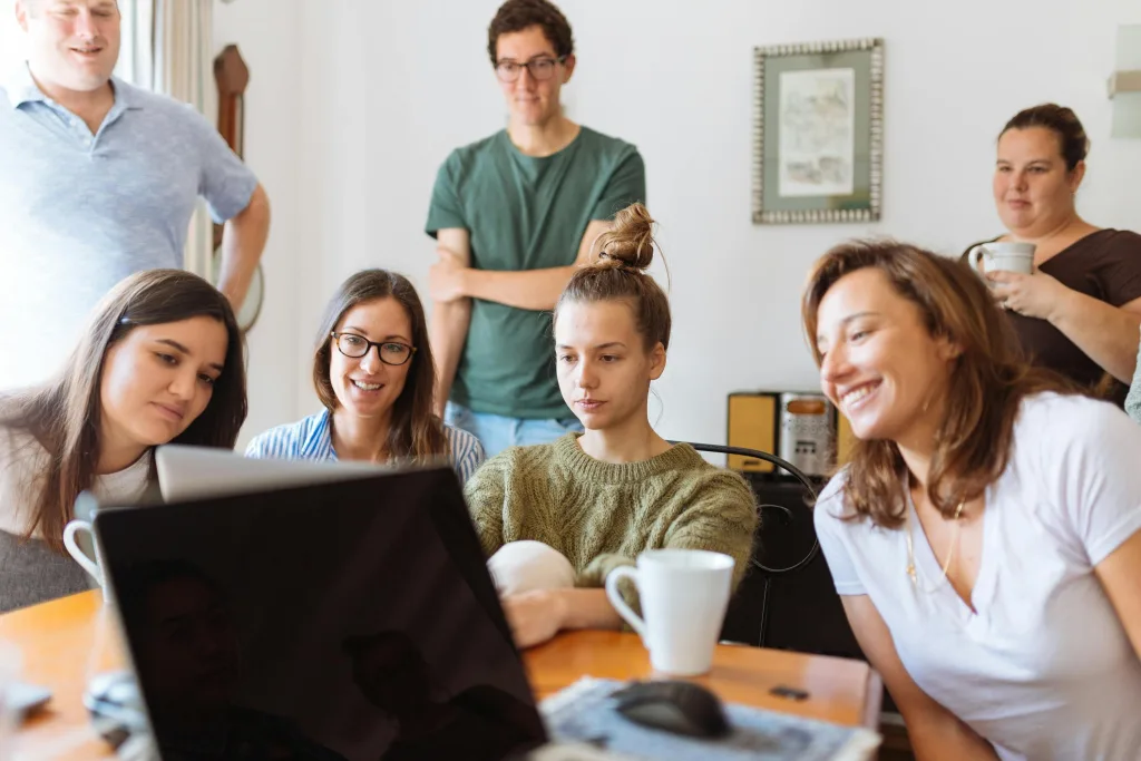 Family collected around dining table focussed on laptop on the table